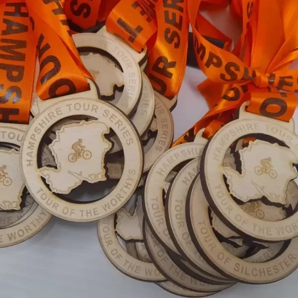 A group of wooden cycling medals with orange ribbons.