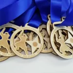 A group of wooden medals with blue ribbons.