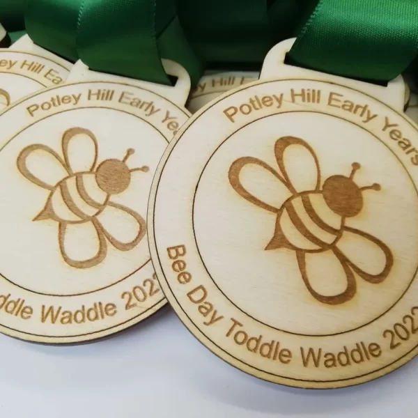 A group of wooden medals with bees on them, perfect for Sports Day.