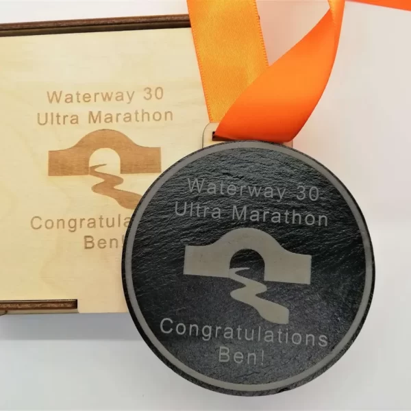 A medal with an orange ribbon and a wooden box.
