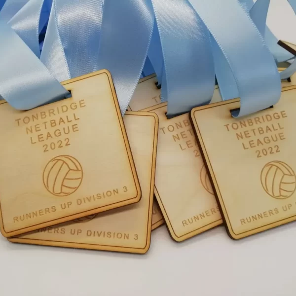 A group of wooden volleyball trophies with blue ribbons resembling swimming medals.