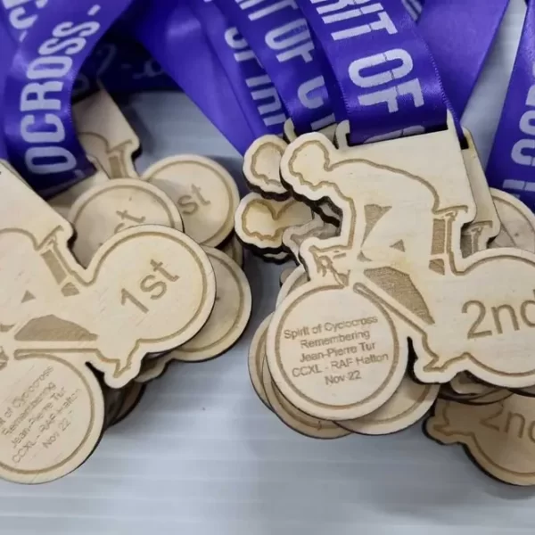 A group of wooden cycling medals with a purple ribbon.