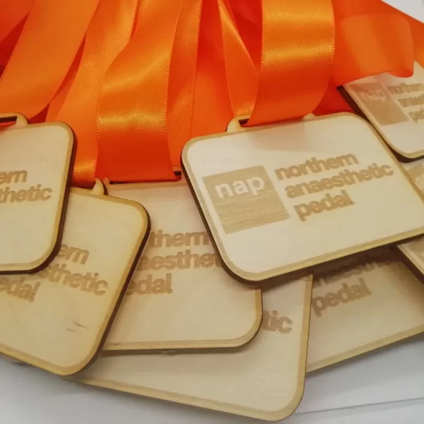 A collection of wooden medals adorned with vibrant orange ribbons.