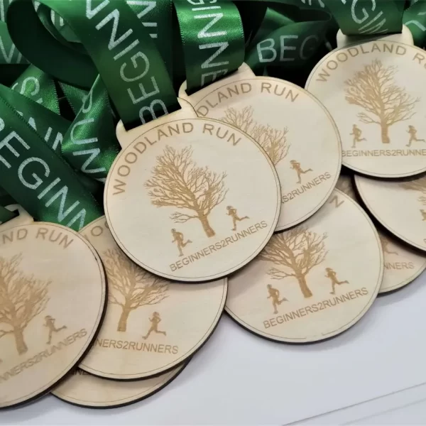 A group of running medals with green ribbons made out of wood.