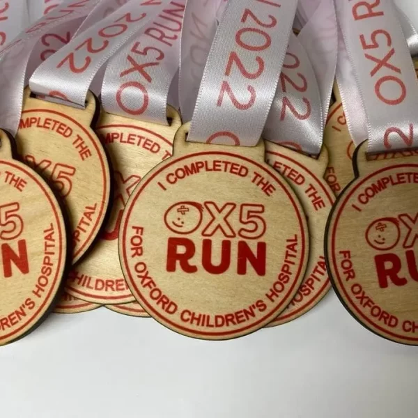 A group of running medals with the word ox5 engraved on them.