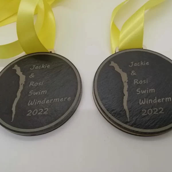 Two swimming medals with yellow ribbons on them.
