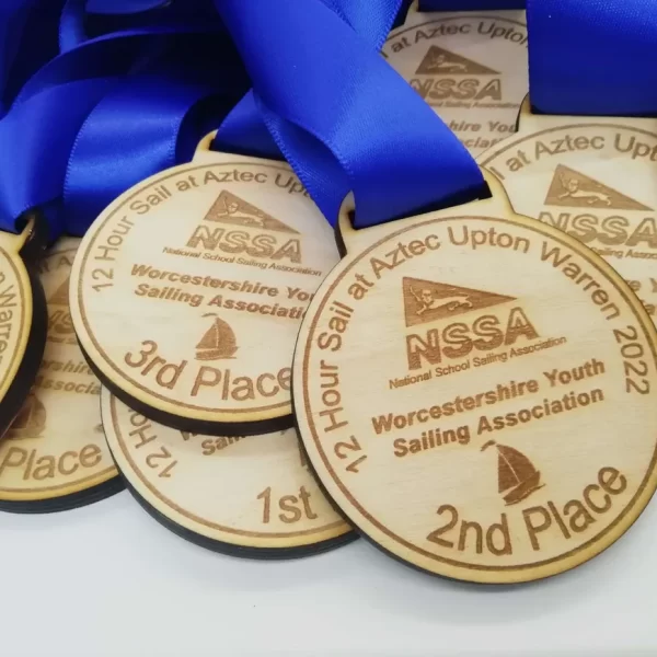 A group of sailing medals with blue ribbons on them.