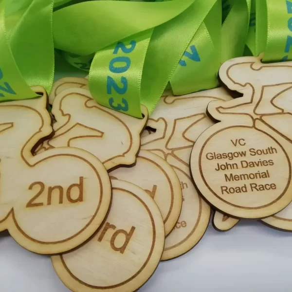 A group of wooden Cycling Medals with green ribbons.