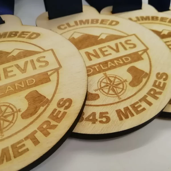 Four wooden climbing medals featuring the word "Nevis" for climbers in Scotland.