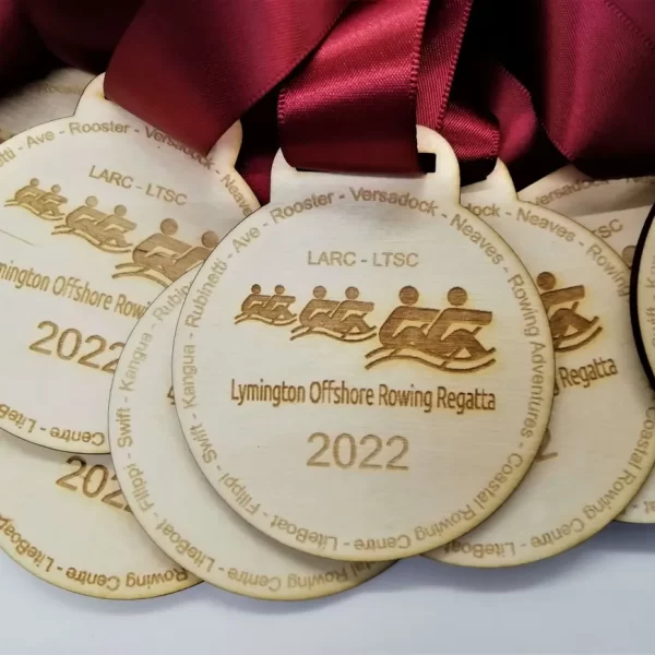 A group of wooden medallions with ribbons on them, perfect for sailing medals.
