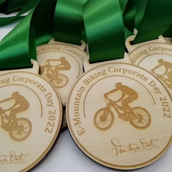 A group of wooden cycling medals with green ribbons.