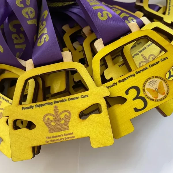 A group of wooden medals with a purple ribbon on them.