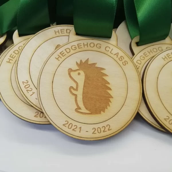 A collection of wooden hedgehog class medals, awarded during Sports Day, featuring vibrant green ribbons.