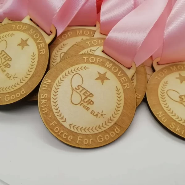 A collection of wooden medals adorned with vibrant pink ribbons.