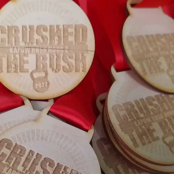 A collection of wooden climbing medals engraved with the empowering phrase "Crushed the Rush".