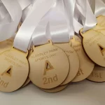 A group of wooden medals with white ribbons.