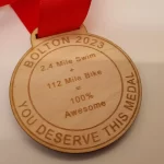 A wooden medal with a red ribbon.
