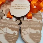 A collection of eco friendly medals made from wood, adorned with vibrant orange ribbons.