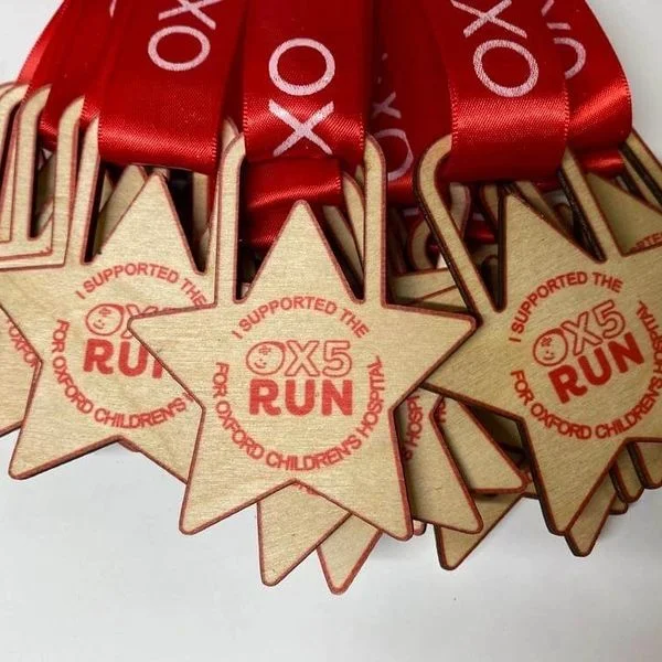 A collection of personalized wooden medals adorned with vibrant red ribbons.