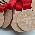 A group of eco friendly wooden medals with red ribbons.