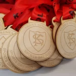 A group of wooden medals with red ribbons.