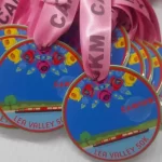 A group of pink eco-friendly medals with ribbons on them.