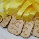A group of wooden medals with yellow ribbons.
