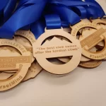 A group of wooden medals with blue ribbons.