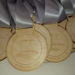 A group of wooden medals with silver ribbons.