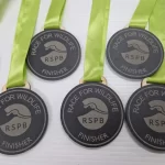 Five medals with green ribbons on them.