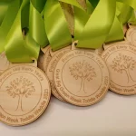 A group of wooden medals with green ribbons.