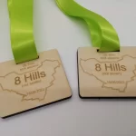 Two wooden medals with green ribbons.