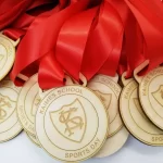 A group of wooden medals with red ribbons.