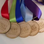 Five wooden medals with ribbons on them.