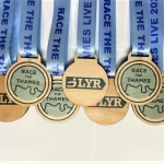 A set of wooden race medals with blue ribbons.