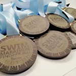 A group of medals with the words swim marathon finisher.