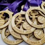 A group of wooden medals with a purple ribbon.