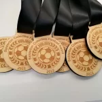 Five wooden soccer medals with black ribbons.