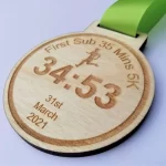 A wooden medal with a green ribbon.