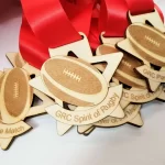 A group of wooden medals with footballs on them.