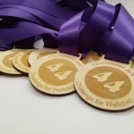 Four wooden medals with purple ribbons.