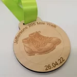 A wooden medal with an image of a pair of hiking boots.