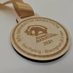 A wooden medal with the name mrs mammoth marathon.