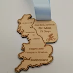 A wooden medal with a blue ribbon and a map of england.