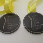 Two medals with yellow ribbons on them.