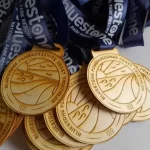 A group of Eco Friendly medals with blue ribbons on them.