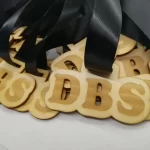 A bunch of wooden letters with black ribbons on them.