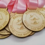 A group of wooden medals with a pink ribbon.