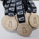 Five wooden medals with black ribbons on them.