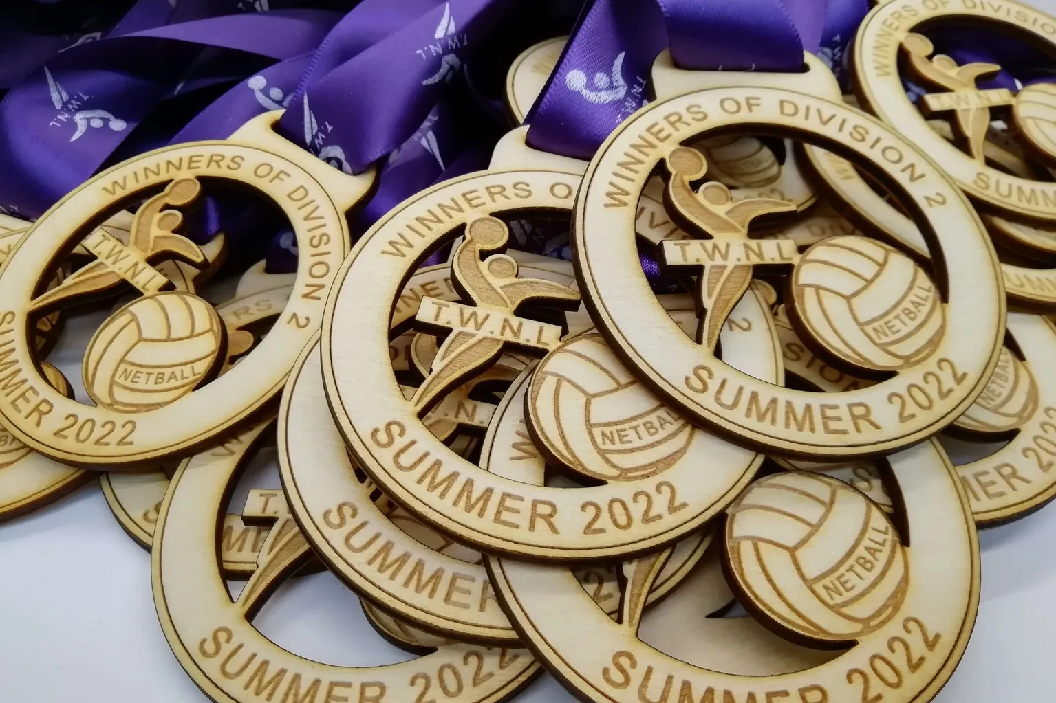 Customised volleyball medals on a purple ribbon.